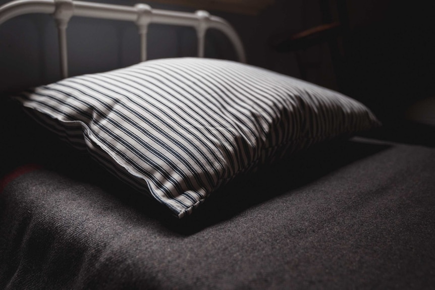 A close up of a pillow on an old hospital bed.