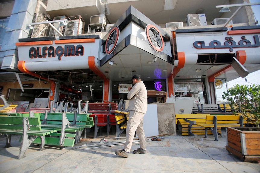 A man inspects the site of a car bomb which exploded outside the ice-cream shop in Baghdad.