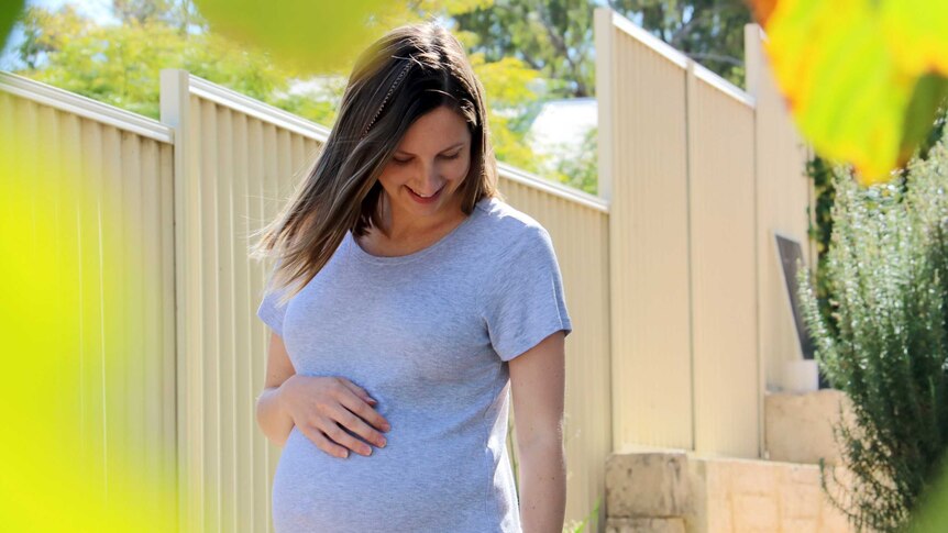 A pregnant Hannah Warren strolls through her backyard.