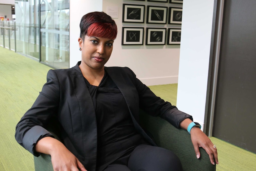 Dr Darshini Ayton sitting in a chair.