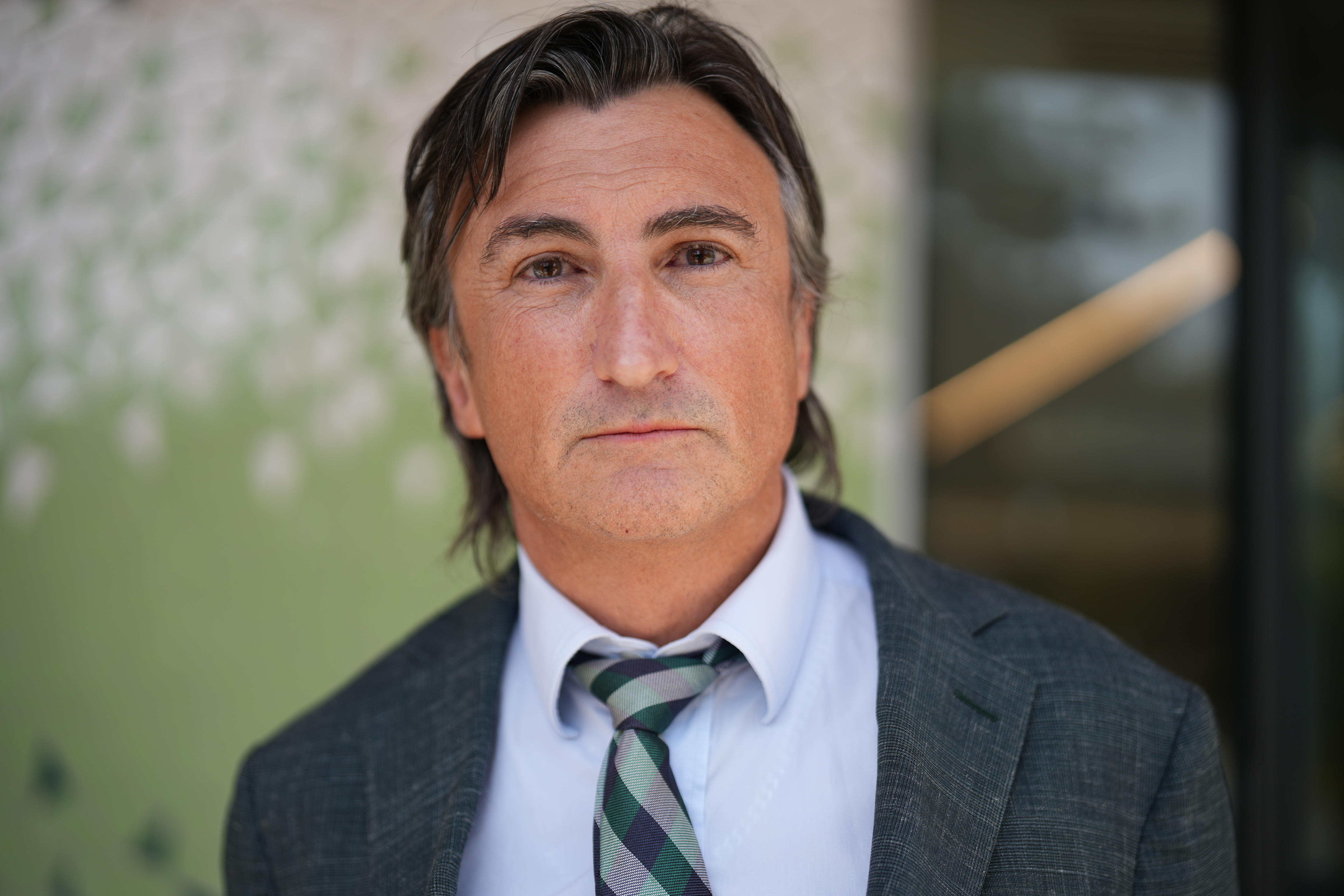 Um homem vestido com terno cinza e gravata.