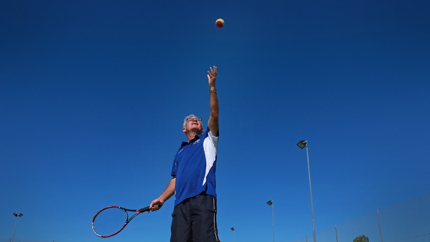 Man throwing tennis ball above his head