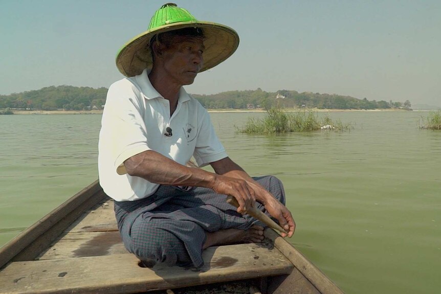 U Maung Lay sits at the end of his long, wooden fishing boat looking out to the water