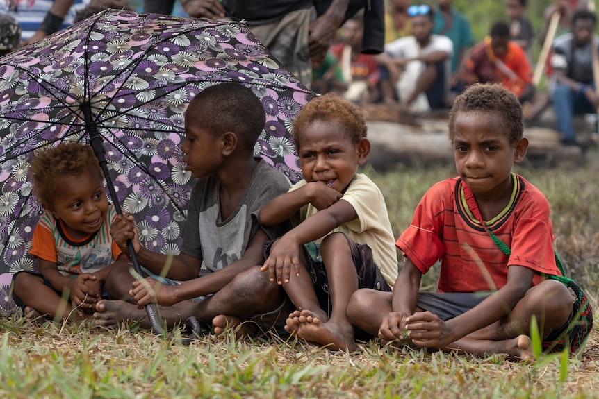 Children sit on the ground.