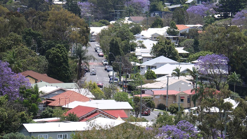 Houses, trees, rooftops, and showing traffic driving on a hilly street in Brisbane on October 31, 2018.
