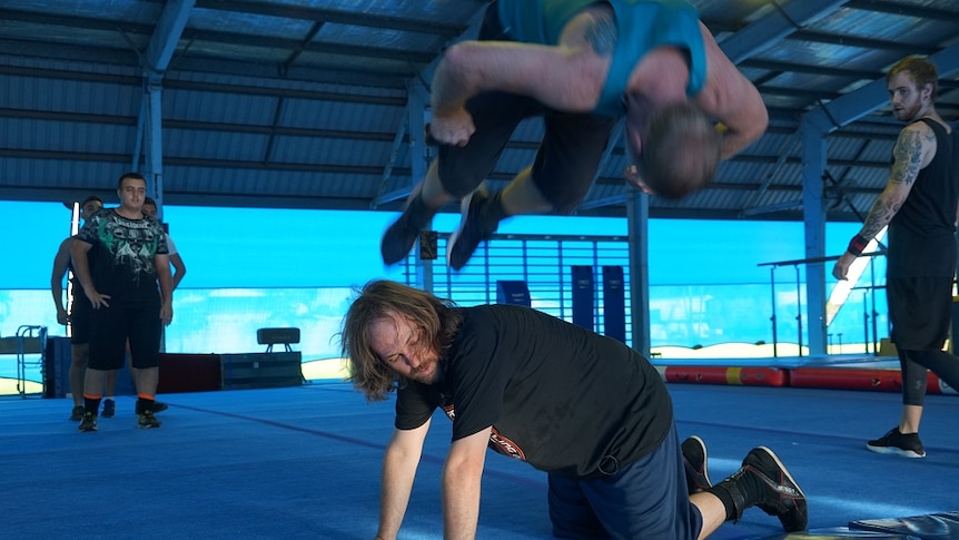 A man leaps over another in a crawling position