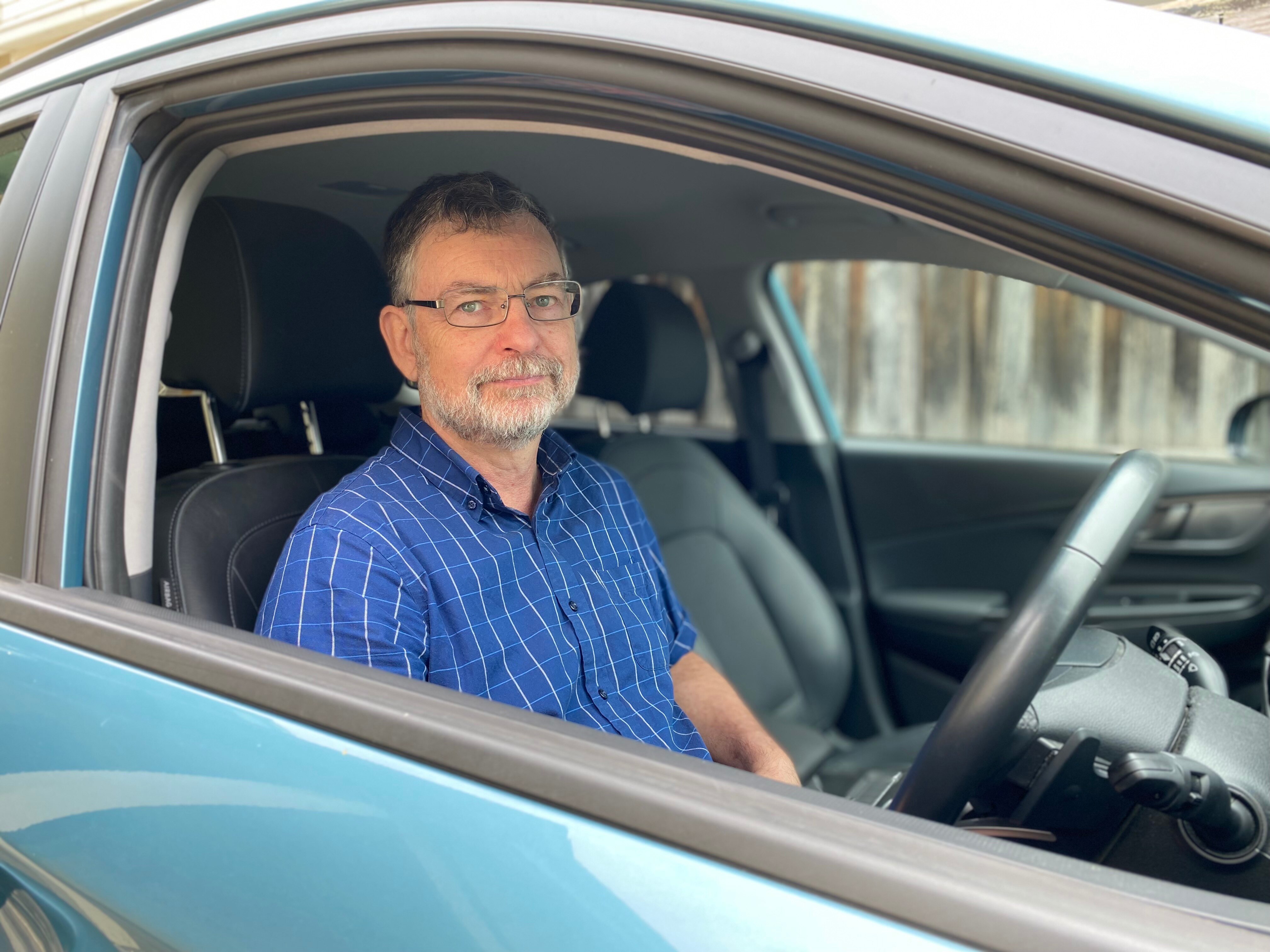 A man looks at the camera while seated in his car.