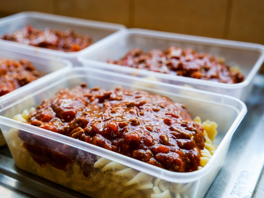 Four plastic containers filled with spaghetti and pasta