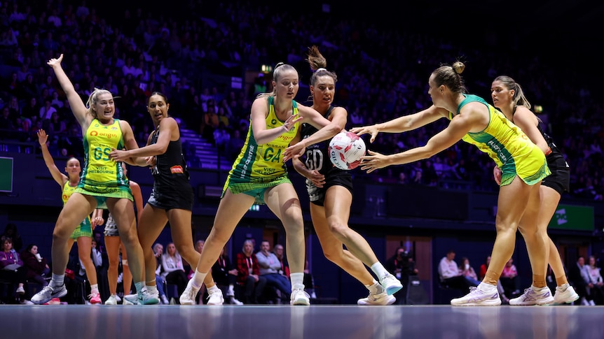 A group of Australian and New Zealand netballers contest the ball during an international match.