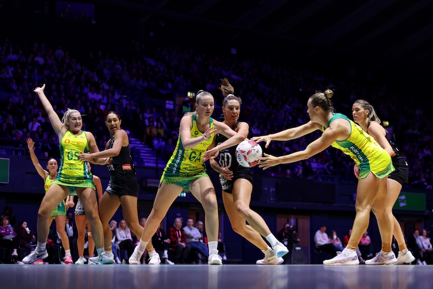 A group of Australian and New Zealand netballers contest the ball during an international match.