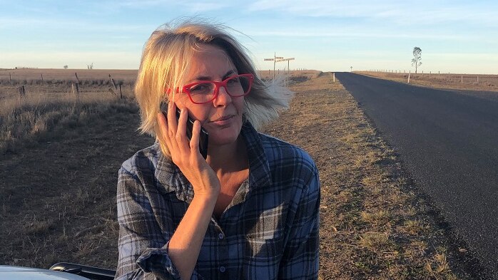 Shanna Whan, creator of Sober in the Country, standing on the side of the highway with a phone to her ear.
