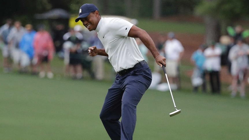 Tiger Woods clenches his fist while holding a putter