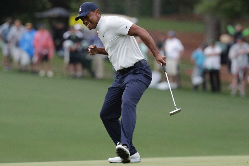 Tiger Woods clenches his fist while holding a putter