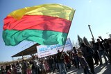 A Kurdish man waves a large flag of the Kurdish People's Protection Units.