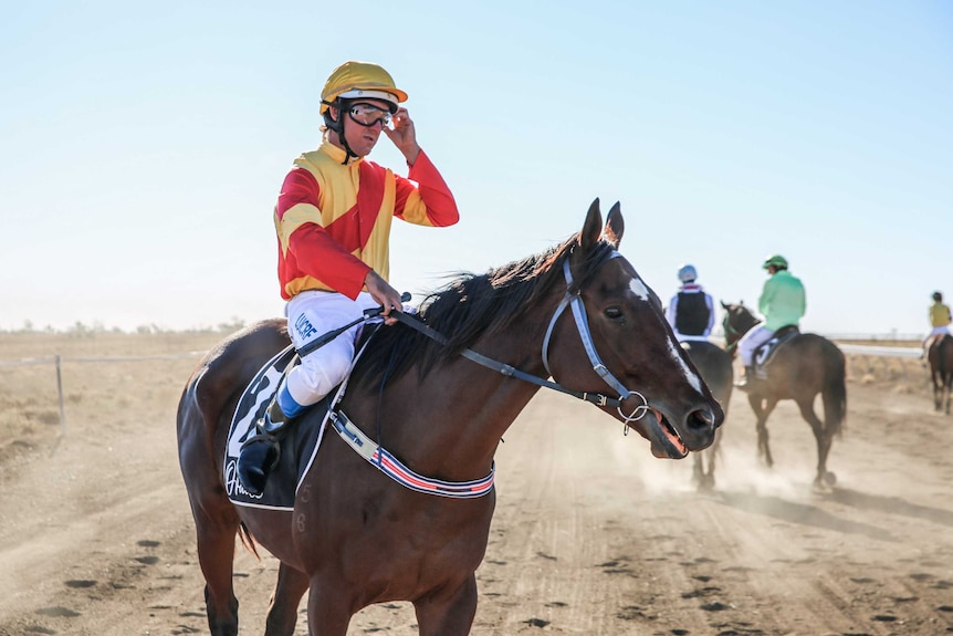 A male jockey sits on a horse.