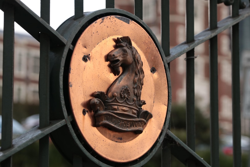A close up of a horse logo on a fence.