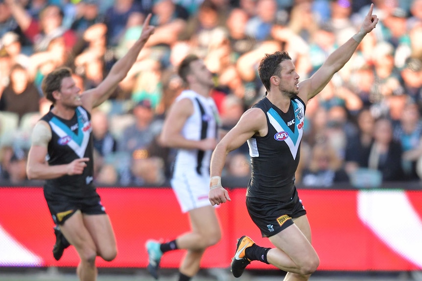 Travis Boak raises his left arm in the air as he celebrates a goal for Port Adelaide.