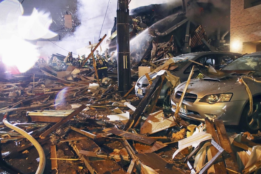 Japan firefighters hose an explosion scene covered in rubble