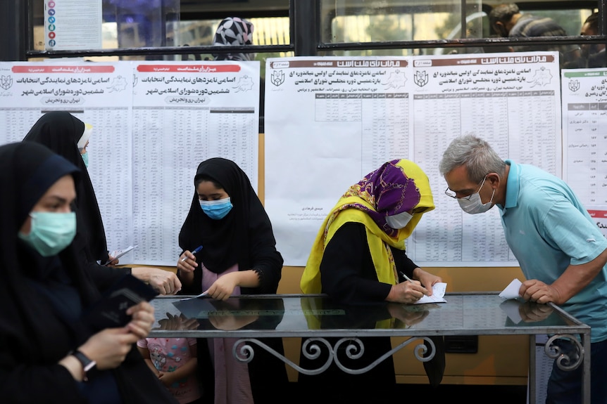 Women go through the list of candidates before giving their vote in Tehran on June 18.