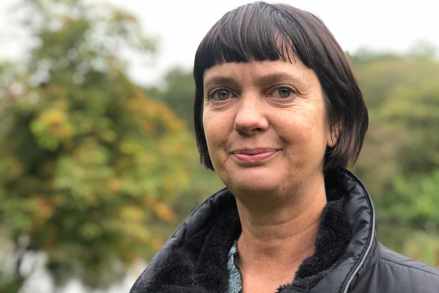 A woman standing in a park wearing a puffer jacket