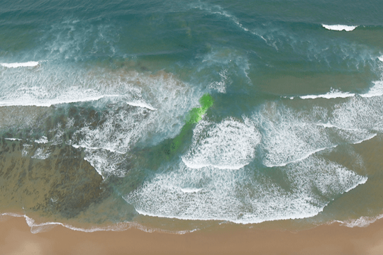 Blue green coloured water between white capped waves indicating a rip. 