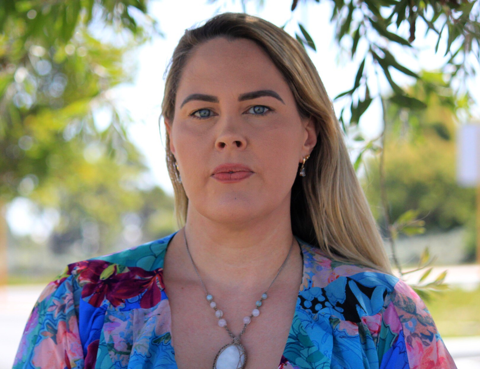 A head-shot of a woman in her late 30's with blond hair, and a serious expression.