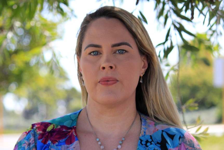 A head-shot of a woman in her late 30's with blond hair, and a serious expression.