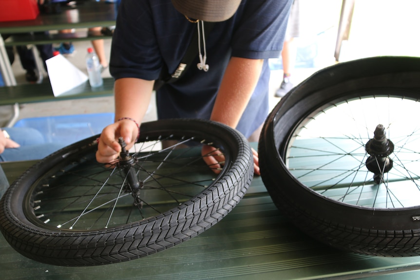 Boy examines the hub of a spoked bike wheel