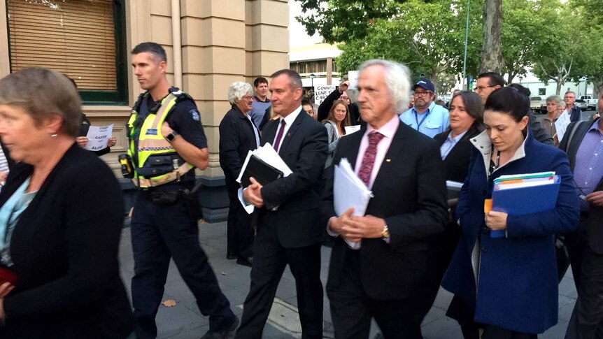 Police escort City of Greater Bendigo CEO Craig Niemann and councillor Rod Fyffe to a council meeting at the Bendigo Town Hall