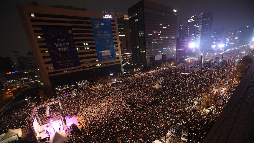 Aerial shot of thousands of people holding candles in central Seoul.
