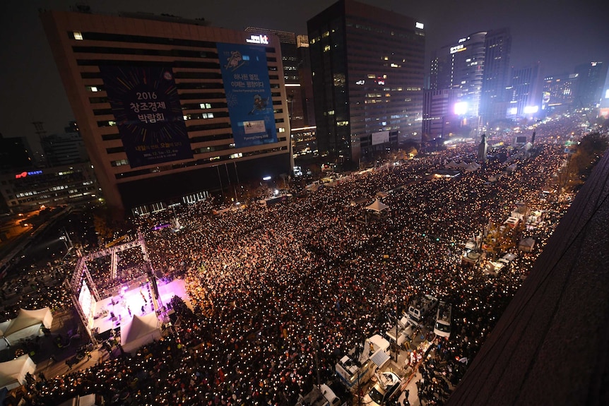 Aerial shot of thousands of people holding candles in central Seoul.