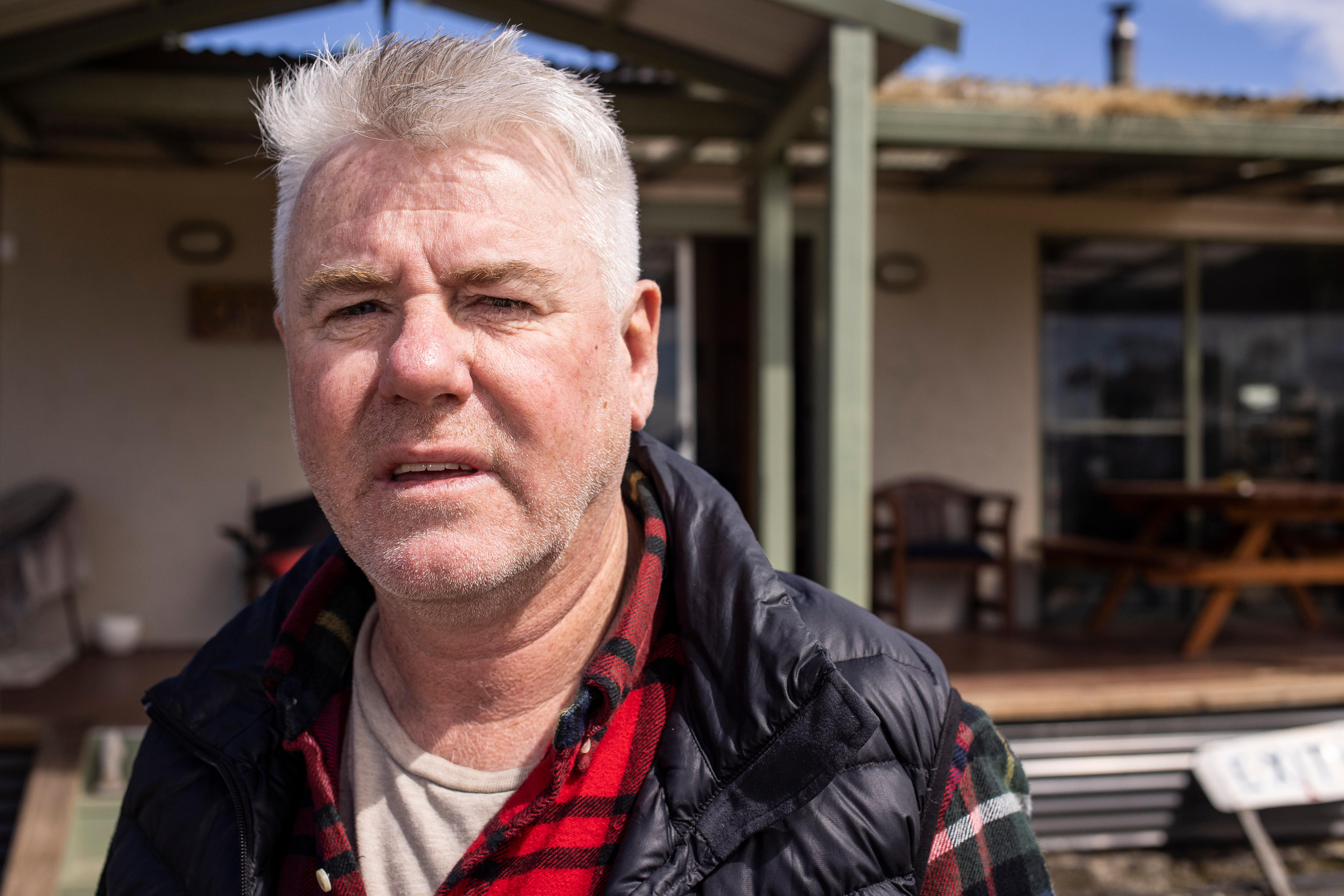 A man stands in front of a house.