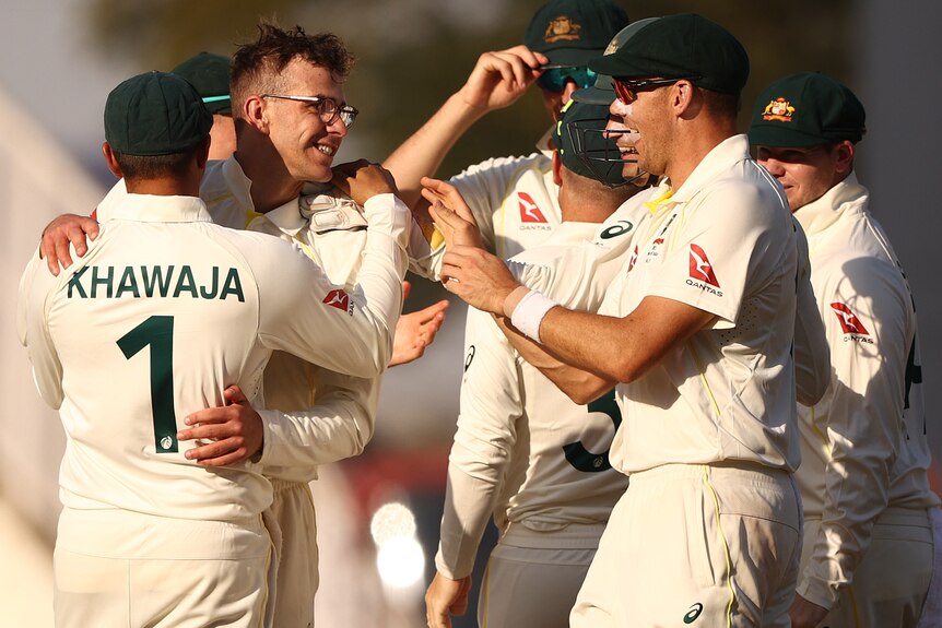 A group of Australian male cricketers celebrating taking an India wicket.