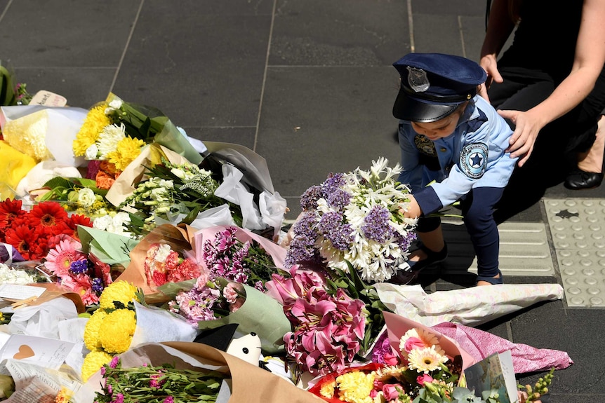 A woman and child lay flowers at a memorial in Bourke Street for the victims of the car rampage.