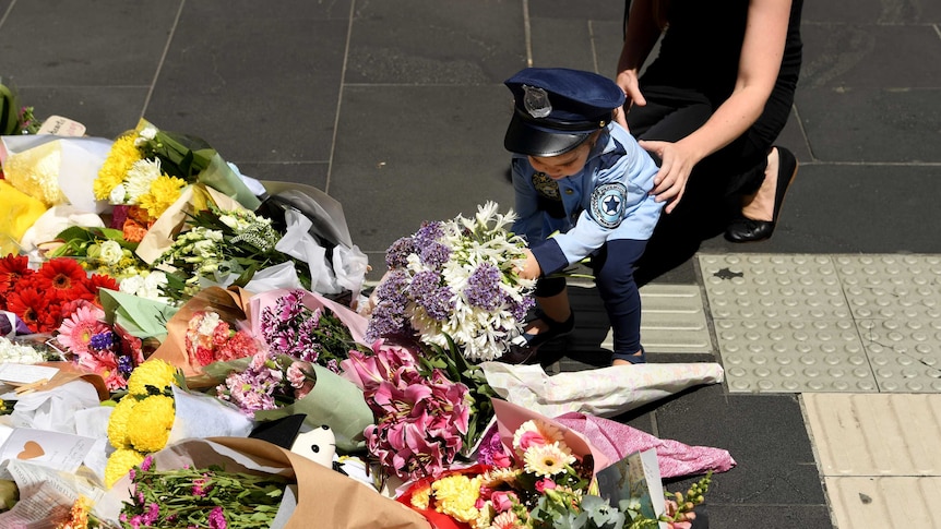 A woman and child lay flowers at a memorial in Bourke Street for the victims of the car rampage.
