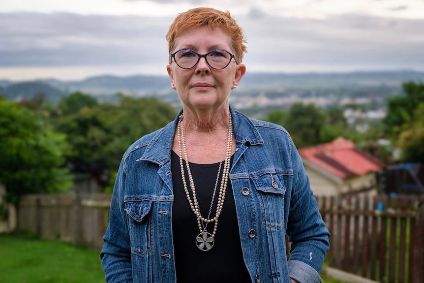 A woman wearing a denim jacket over a black top.