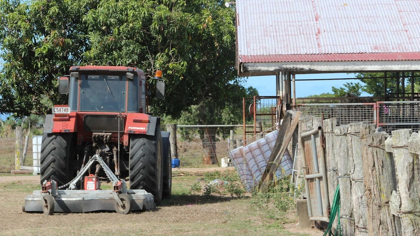 A large red tractor parked next to cattle yards on a farm in north Queensland.