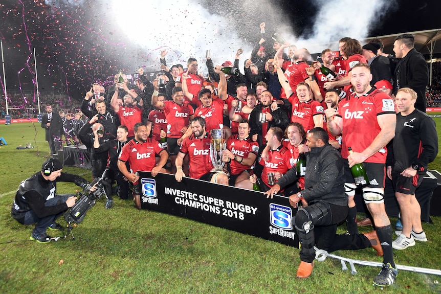 As confetti sprays around them, a Super Rugby team celebrates with the trophy.