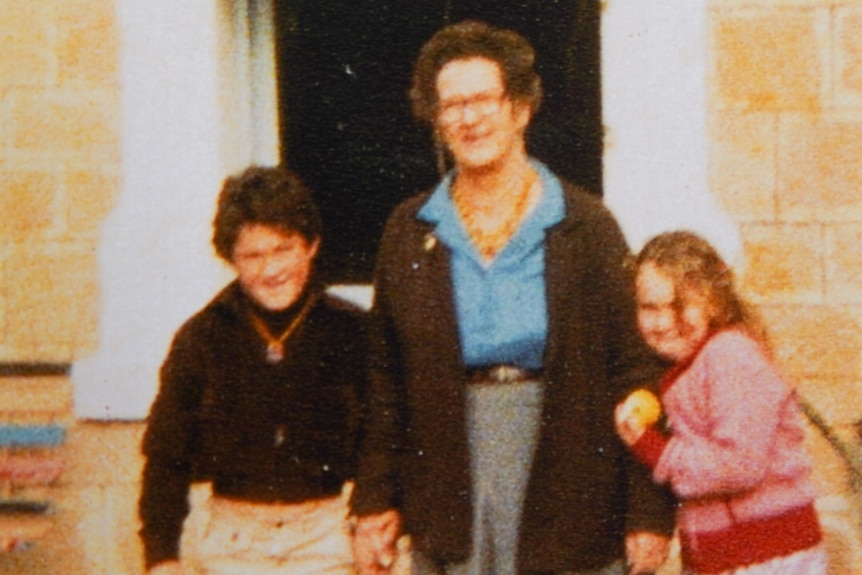 An old photo of a sister, brother and grandmother.