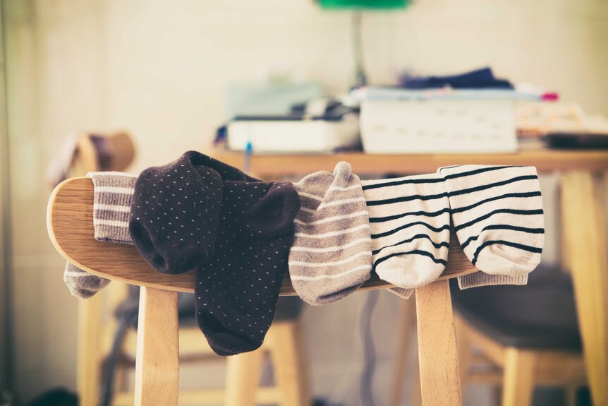 Pairs of sock arranged over the back of a wooden chair.