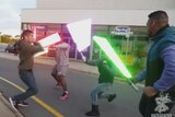 Men wield light saber toys in a shopping centre car park.