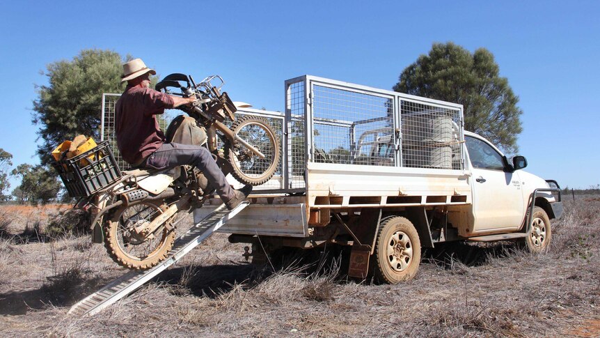 Don Sallway rides his motorbike onto the back of his ute.