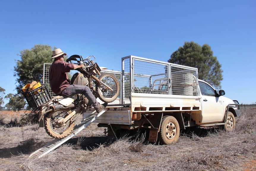 Don Sallway rides his motorbike onto the back of his ute.