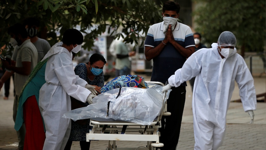 Workers transport a body on a stretcher as family members cry