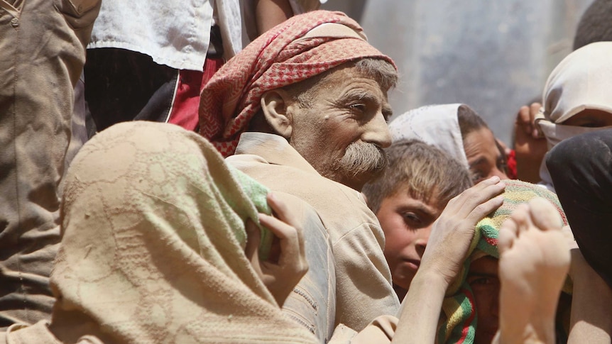 Yazidi man and children covered in dust ride in a truck fleeing Islamic State militants in northern Iraq