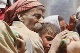 Yazidi man and children covered in dust ride in a truck fleeing Islamic State militants in northern Iraq