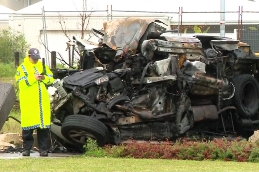 Wreckage of a Toyota Kluger with a policeman investigating