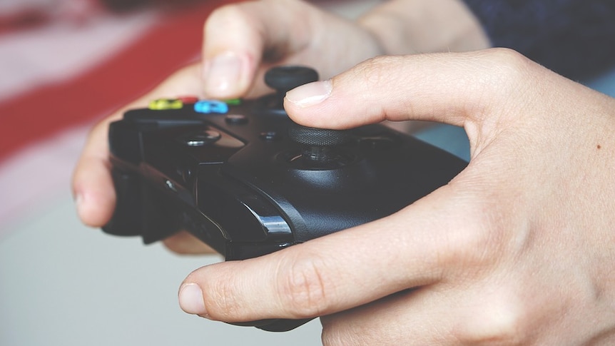 A close up image of the hands and controller of a boy playing video games.