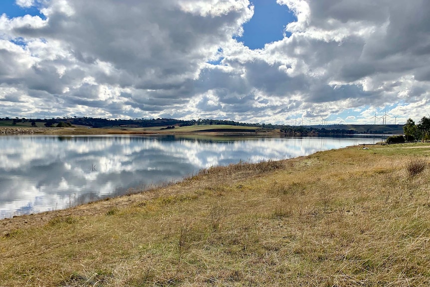 Pejar Dam with water, green grass, windmills and clouds in the sky