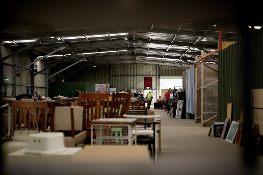 A large shed with a range of used furniture including wooden chairs.